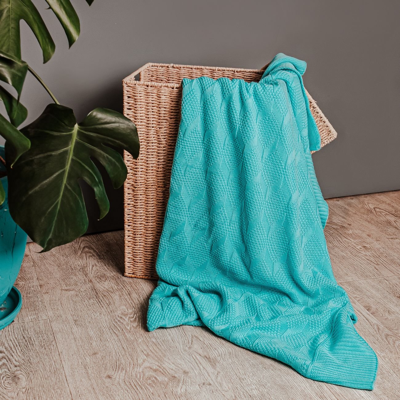 Woven basket with a textured blanket and houseplant, home decor styling.